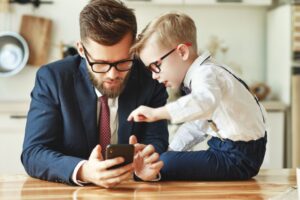 professional father looking at cellphone with son